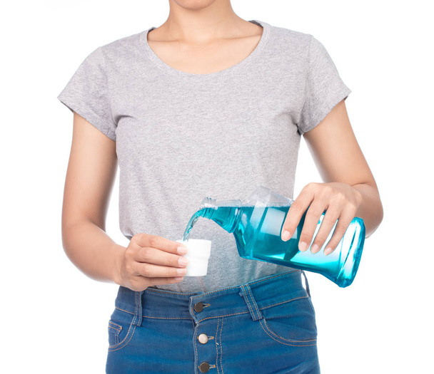 meisje dragen blanco grijs t-shirt, jeans houdt een mondwater fles geïsoleerd op witte achtergrond. - Foto, afbeelding
