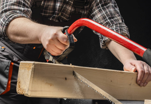 primer plano de Carpintero aserrando una tabla con una sierra de madera de mano
. - Foto, Imagen