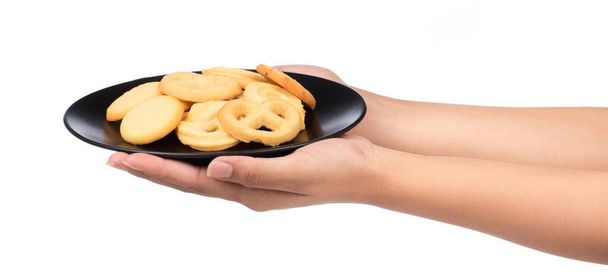 mão segurando biscoitos de manteiga em um prato isolado no fundo branco
 - Foto, Imagem