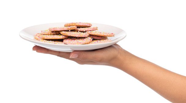 mão segurando biscoitos de morango com cobertura polvilhe no prato isolado no fundo branco
. - Foto, Imagem