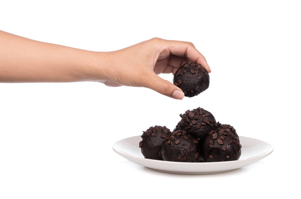 mano sosteniendo bola de chocolate en el plato aislado sobre un fondo blanco
 - Foto, Imagen