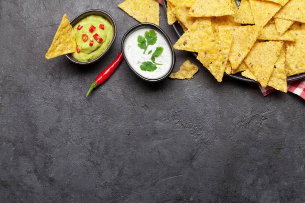 Mexikói nachos chips különböző szószokkal - guacamole és tejföl. Top view lakás feküdt kő asztal fénymásoló hely - Fotó, kép
