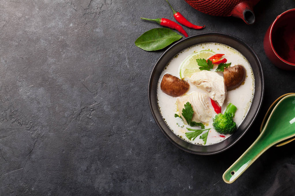 Soupe traditionnelle thaïlandaise Tom Kha avec poulet, champignons, lait de coco et épices chaudes. Avec théière verte et bol. Vue supérieure avec espace de copie
 - Photo, image