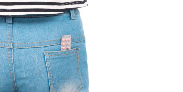 таблетки контролю народжуваності в задній кишені синіх джинсів ізольовані на білому тлі
 - Фото, зображення