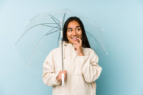 Joven mujer asiática sosteniendo un paraguas relajado pensando en algo mirando un espacio de copia
. - Foto, Imagen