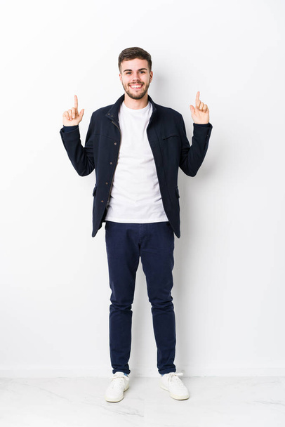 Full body young caucasian man isolated indicates with both fore fingers up showing a blank space. - Foto, immagini