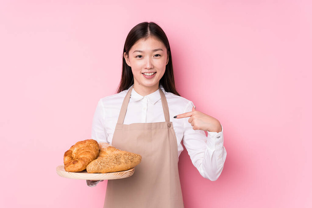 Young chinese baker woman isolated person pointing by hand to a shirt copy space, proud and confident - Photo, Image