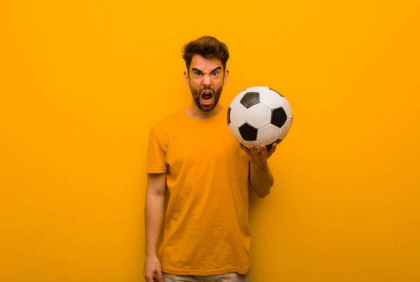Giovane giocatore di calcio uomo urla molto arrabbiato e aggressivo - Foto, immagini