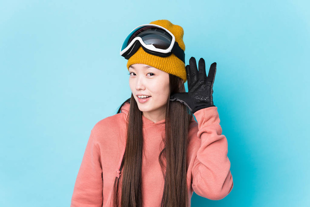 Jeune Chinoise vêtue de vêtements de ski isolée essayant d'écouter un potins
. - Photo, image