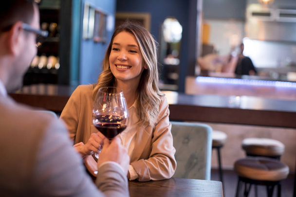 Młoda para ciesząca się obiadem w restauracji z kieliszkami czerwonego wina - Zdjęcie, obraz