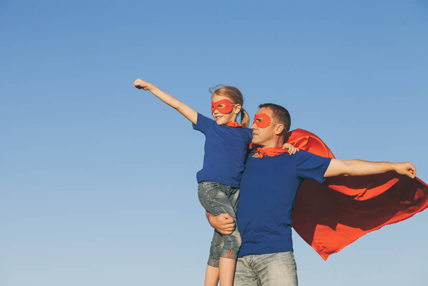 Father and daughter playing superhero at the day time. People having fun outdoors. Concept of friendly family. - Foto, Imagen