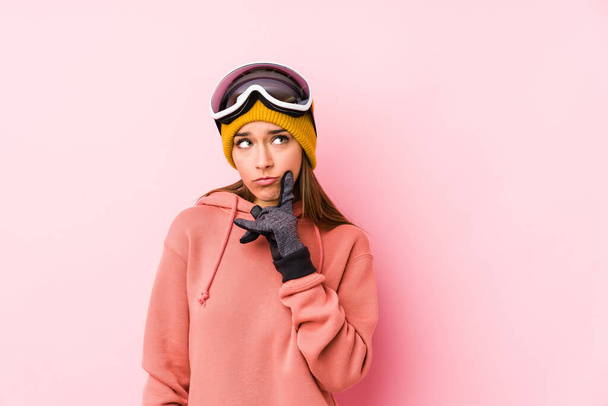 Νεαρή καυκάσια γυναίκα που φοράει ρούχα του σκι απομονωμένη κοιτάζοντας πλάγια με αμφίβολη και σκεπτικιστική έκφραση. - Φωτογραφία, εικόνα