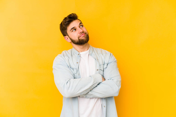 Young caucasian man isolated on yellow background dreaming of achieving goals and purposes - 写真・画像