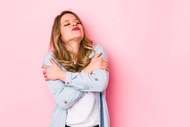 Young caucasian woman isolated on pink background hugs, smiling carefree and happy. - Photo, Image
