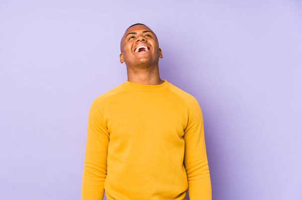 Jonge latijn man geïsoleerd op paarse achtergrond ontspannen en gelukkig lachen, nek gestrekt tonen tanden. - Foto, afbeelding