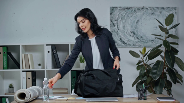 donna d'affari mettendo bottiglia d'acqua in borsa, prendendo tappetino fitness e andare via
 - Filmati, video