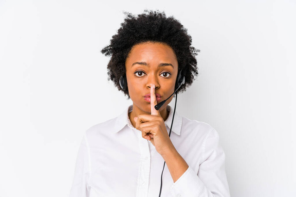Joven afroamericana telemarketer mujer aislada guardando un secreto o pidiendo silencio
. - Foto, Imagen