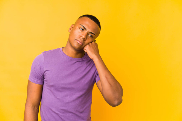 Young latin man isolated on yellow background who feels sad and pensive, looking at copy space. - Foto, afbeelding