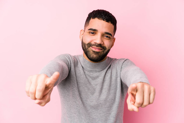 Jonge latijnse man tegen een roze achtergrond geïsoleerde vrolijke glimlachen wijzen naar voren. - Foto, afbeelding