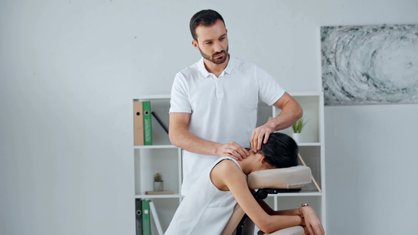красивий масажист робить масаж шиї бізнес-леді на масажному кріслі
 - Кадри, відео