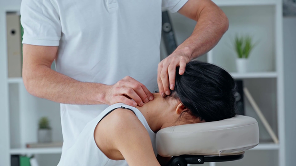 vista recortada de masajista haciendo masaje de cuello a mujer de negocios en silla de masaje
 - Imágenes, Vídeo