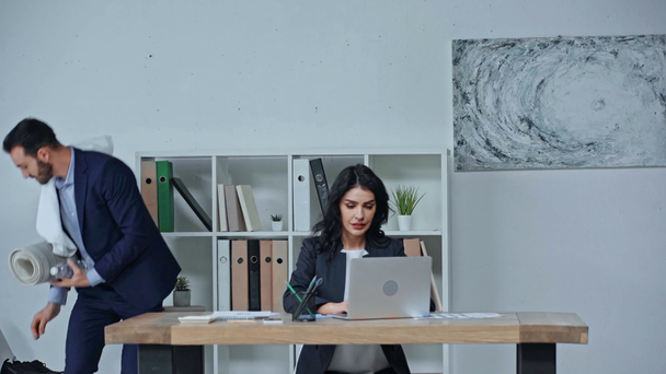 бизнесмен принимает фитнес-мат и полотенце, в то время как деловая женщина печатает на ноутбуке
 - Кадры, видео