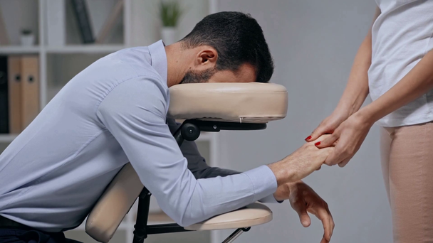 vista ritagliata di massaggiatrice rendendo mani massaggio per l'uomo d'affari in sedia di massaggio
 - Filmati, video
