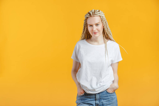 Hipster mode jonge vrouw met kanekalon in wit t-shirt op gele achtergrond - Foto, afbeelding