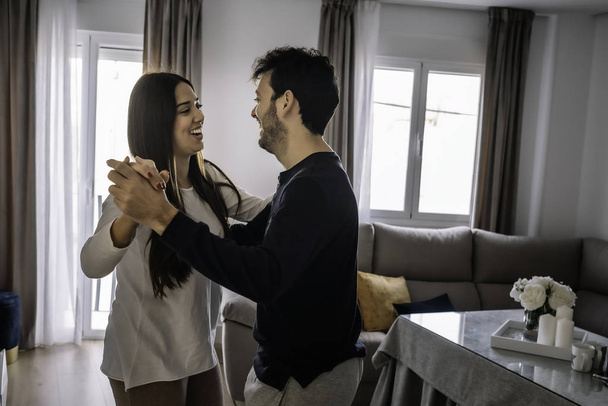 young couple smiling, dancing inside their house - Foto, imagen