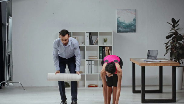 fitness instructor and businessman carrying fitness mats in office - Metraje, vídeo