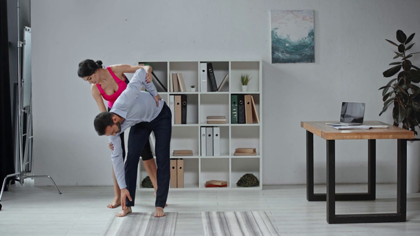 aantrekkelijke trainer instrueren zakenman hoe yoga te oefenen in het kantoor - Video