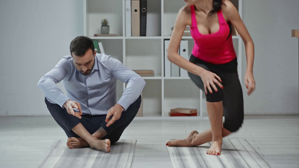 atractivo instructor de yoga mostrando pose de loto al hombre de negocios
 - Metraje, vídeo
