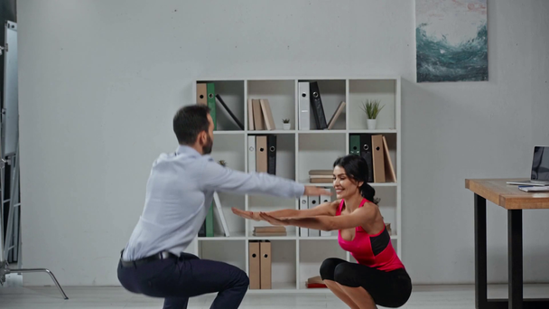 attractive fitness trainer and businessman exercising in office together - Video, Çekim