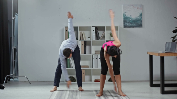 joven instructor de yoga y guapo hombre de negocios ejerciendo juntos en el cargo
 - Metraje, vídeo