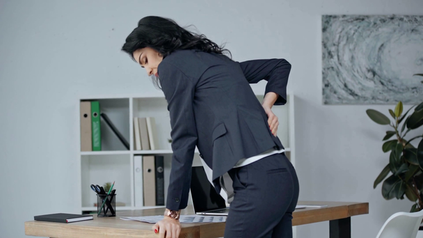 vonzó üzletasszony szenved hátfájás, miközben dolgozik az irodában - Felvétel, videó
