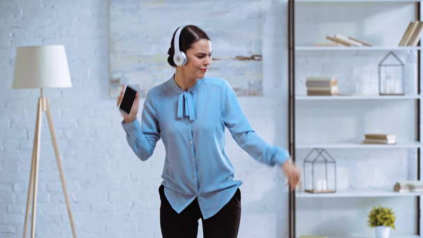 happy businesswoman in wireless headphones dancing in office  - Materiaali, video