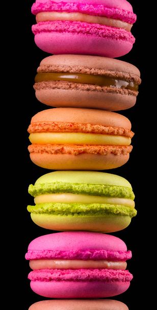 Stack of french colorful macaroons on wooden table isolated on black background - Фото, изображение