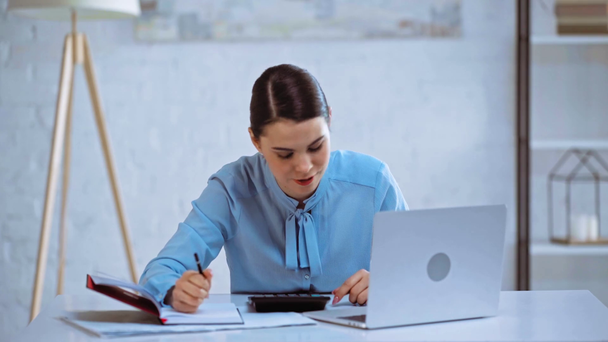 mulher de negócios atraente usando calculadora perto do laptop
  - Filmagem, Vídeo