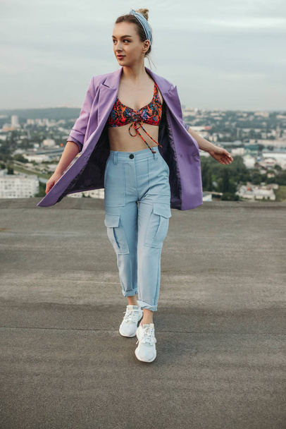 Trendy slim woman walking on rooftop - 写真・画像