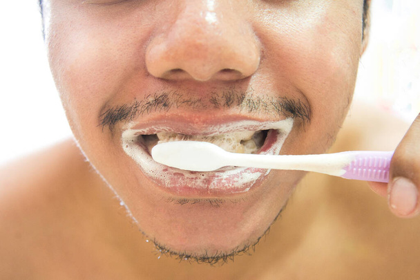 アジア系男性は白地に歯を磨く。歯のケアの概念。健康的なコンセプト. - 写真・画像