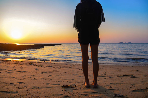Silueta hubené ženy stojí při pohledu na moře a nebe ve večerních hodinách a minout nebo na někoho čeká. Samotná koncepce. - Fotografie, Obrázek