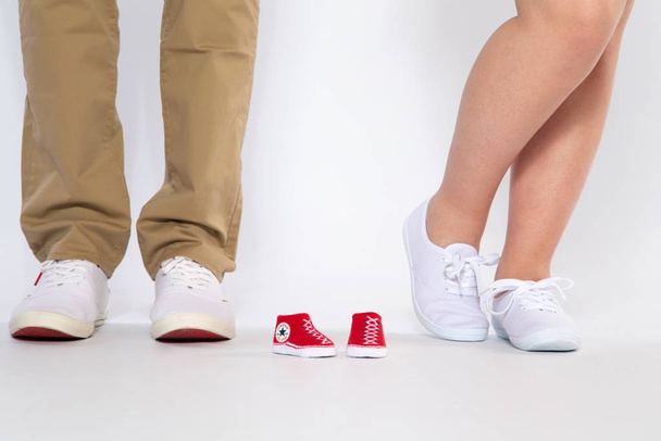 Two pairs of feet from the parents and shoes from an unborn baby, studio - Foto, Imagem