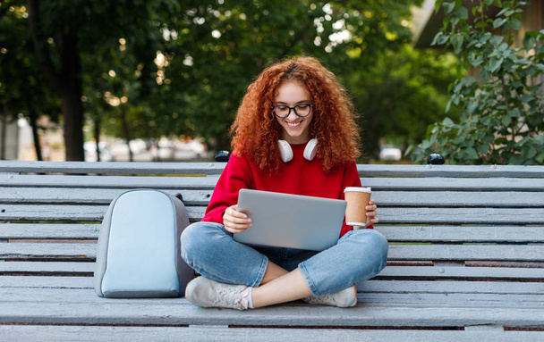 Happy female student enjoying coffee and using laptop - Zdjęcie, obraz