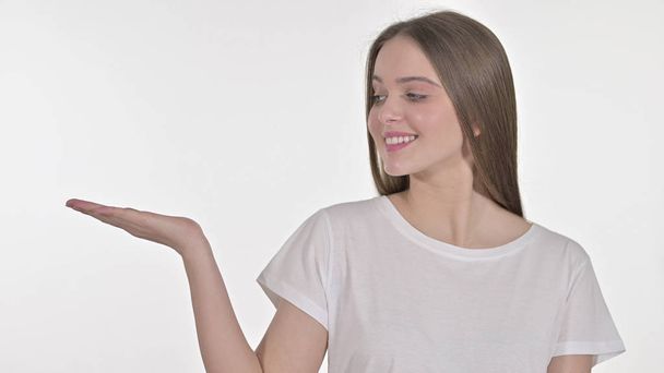 junge Frau zeigt Produkt auf der Hand, weißer Hintergrund - Foto, Bild