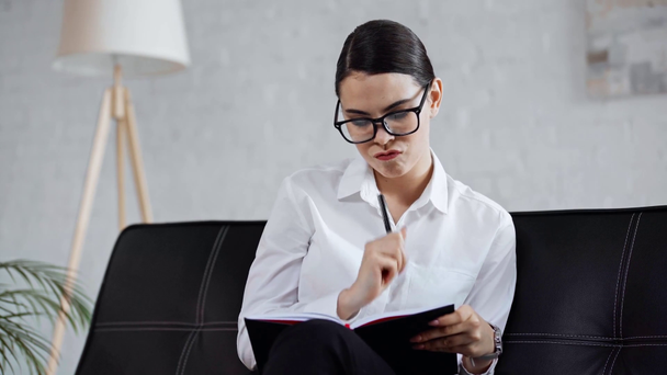 pensive businesswoman smiling and writing in notebook  - Footage, Video