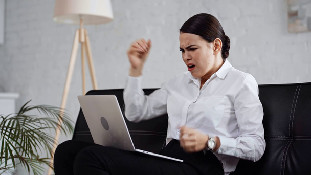 boos zakenvrouw met behulp van laptop terwijl zitten op de bank  - Video