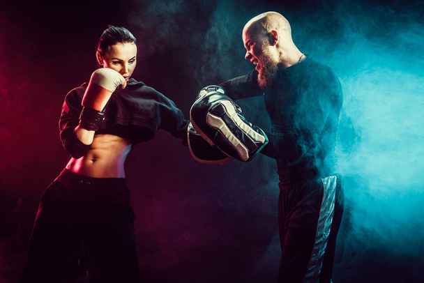 Woman exercising with trainer at boxing and self defense lesson - Foto, afbeelding