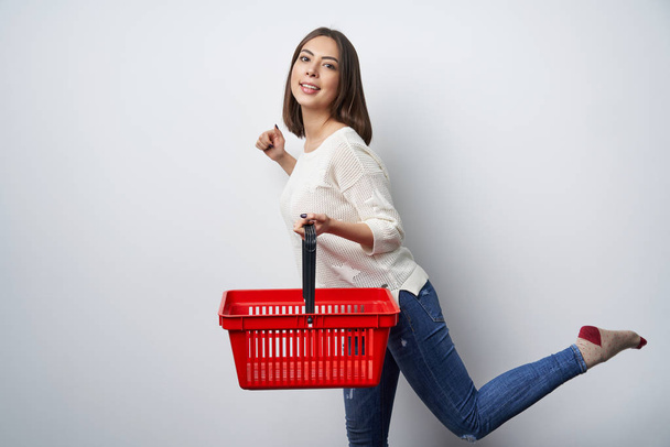 Smiling brunette woman walking with empty shopping basket - Photo, image