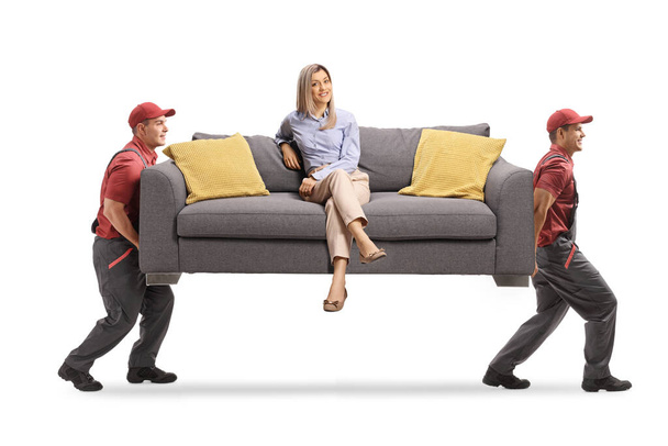 Movers carrying a sofa with a young woman sitting and smiling isolated on white background - Φωτογραφία, εικόνα