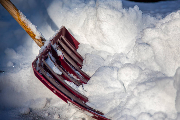 Pala di plastica rossa spingendo cumulo di neve durante l'inverno in Massachusetts, Stati Uniti
 - Foto, immagini